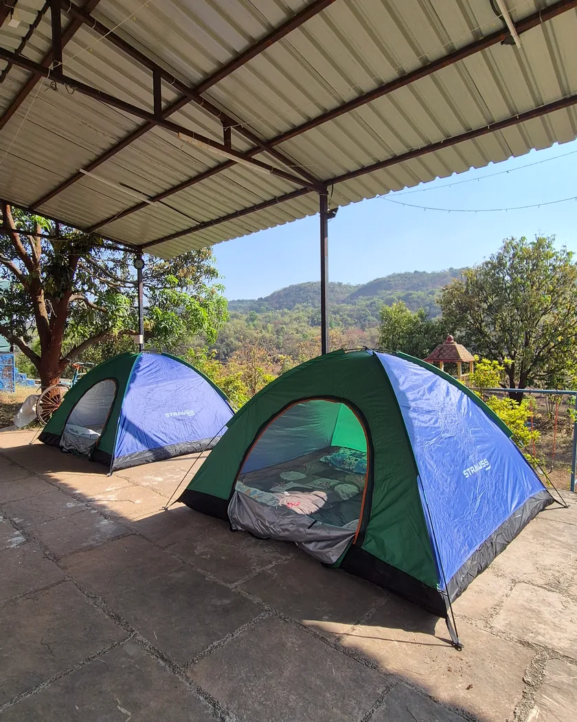 Dome tents for two under a shelter, with the Sahyadri hills beyond.