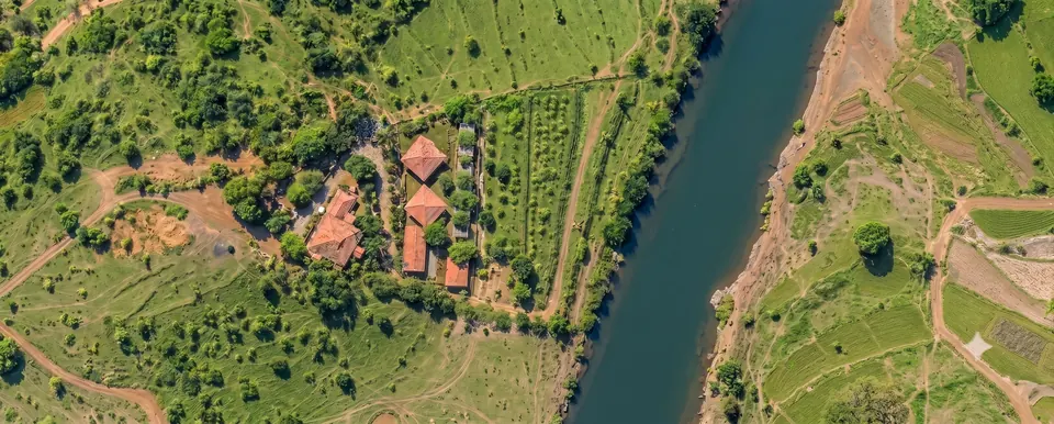 Sujalam Sufalam from above: the cottages and tents among the trees, with the river beyond.
