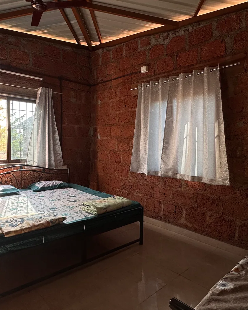 A cottage room at the farmstay, a wide bed by two curtained windows.