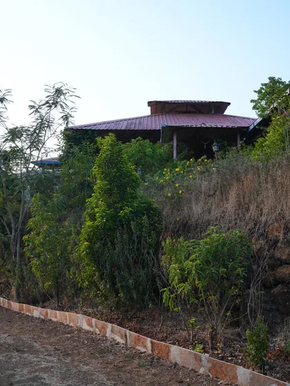 The open dining building under its tiled roof, screened by trees.