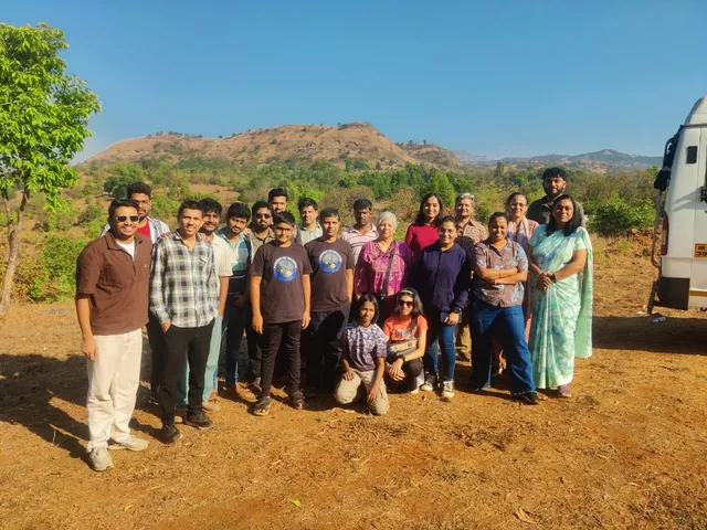A stargazing group gathered on the farm near Rajgad Fort, the hills behind them.