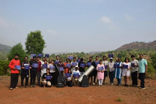 A past stargazing group holding their certificates beside two telescopes.