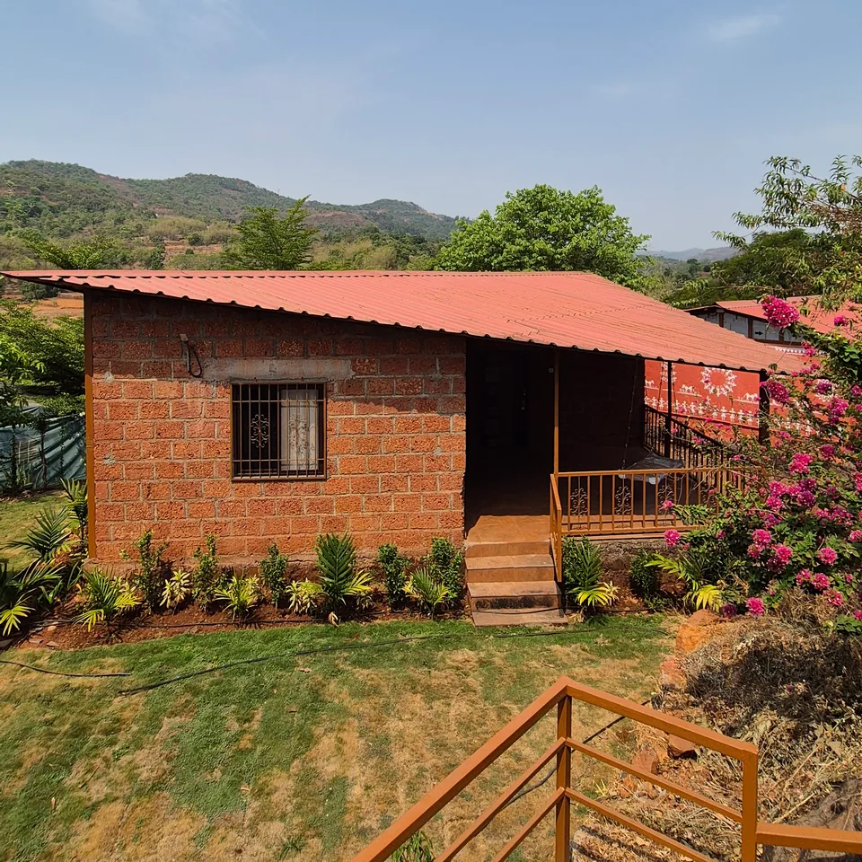 A red-roofed stone cottage on the farm, its verandah hung with bougainvillea, the hills behind.