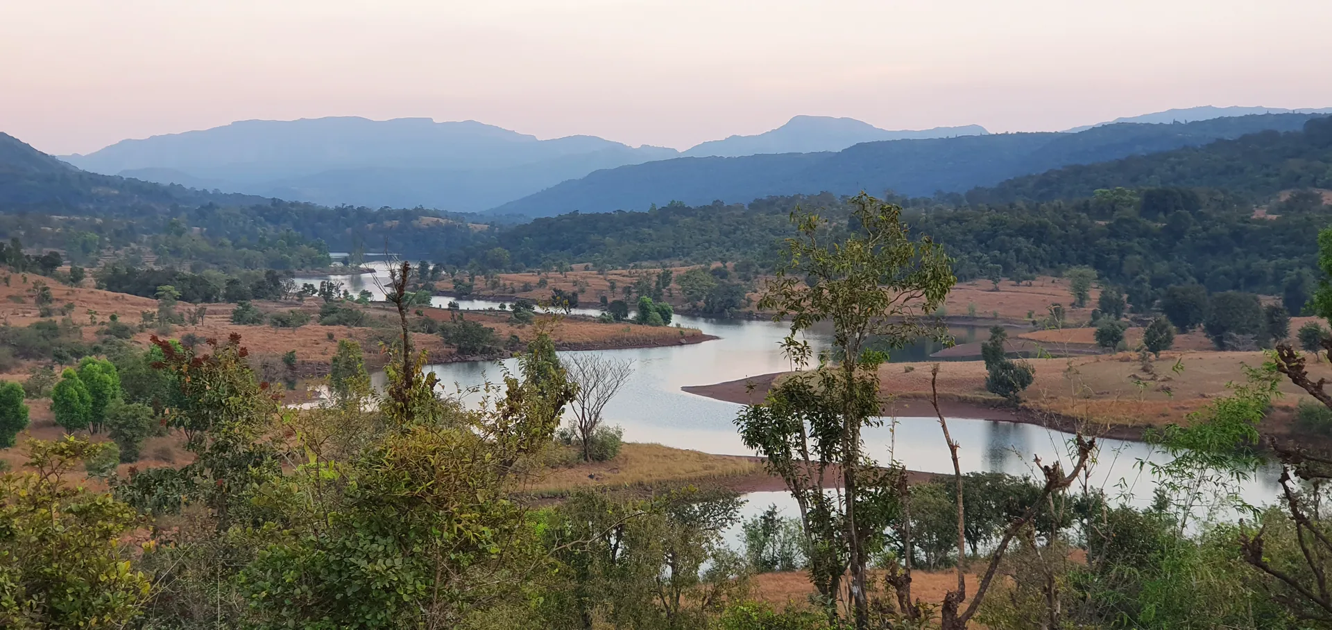 The river winding through the valley near the farm at dusk, the Sahyadri hills fading behind.